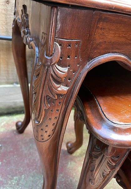 Close-up of a wooden chair with intricate carvings on a blurred background