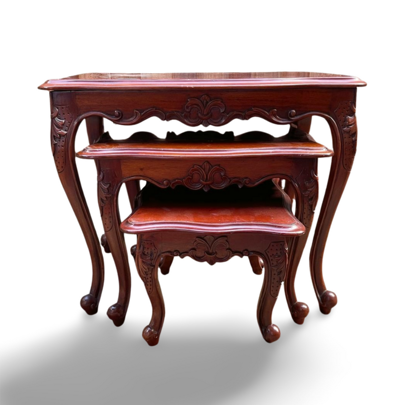 Set of three nested wooden tables with intricate carvings on a white background